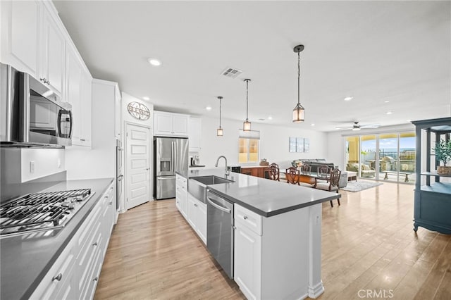kitchen with stainless steel appliances, a sink, recessed lighting, light wood-style floors, and white cabinetry
