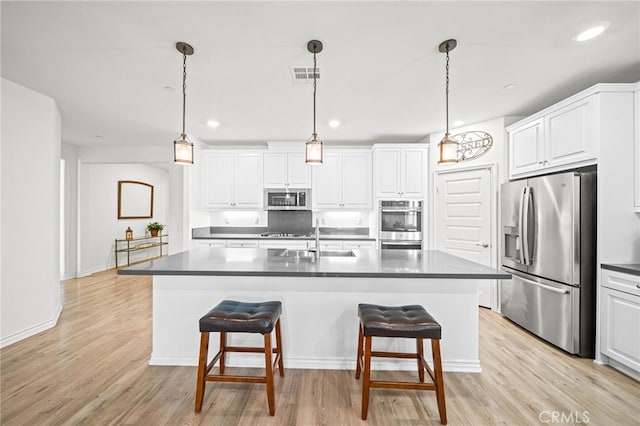 kitchen featuring appliances with stainless steel finishes, a sink, a breakfast bar, white cabinets, and recessed lighting