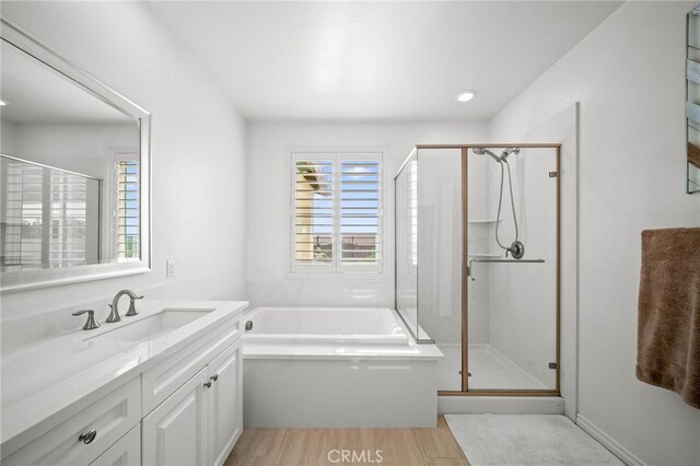 bathroom with a shower stall, wood finished floors, vanity, and a garden tub