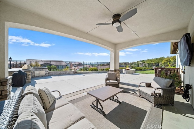 view of patio with exterior kitchen, an outdoor hangout area, fence, and a ceiling fan
