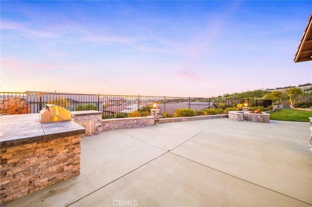 view of patio / terrace with an outdoor kitchen, a fire pit, and a fenced backyard