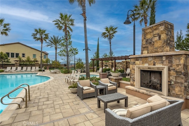 community pool featuring a pergola, a patio area, and an outdoor living space with a fireplace