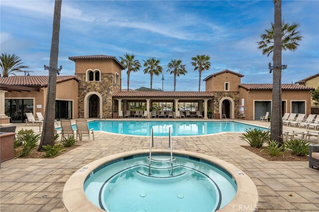 pool with a community hot tub and a patio
