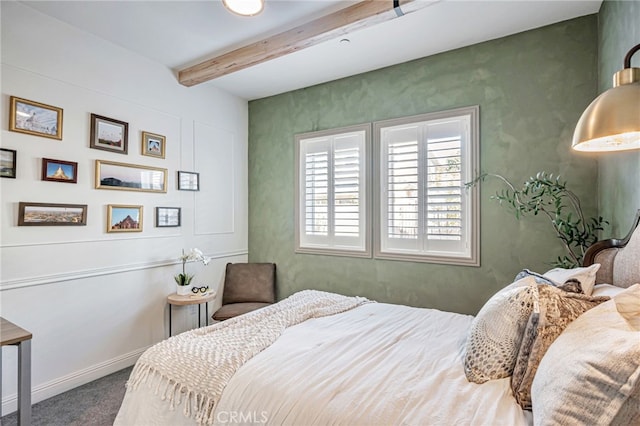 carpeted bedroom featuring baseboards and beamed ceiling