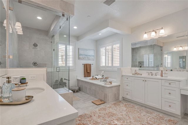 full bathroom with visible vents, a bath, a sink, a shower stall, and two vanities