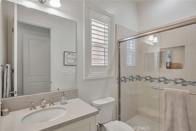 bathroom featuring a stall shower, vanity, and toilet