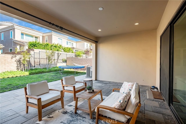 view of patio with central air condition unit, fence, a trampoline, and an outdoor living space