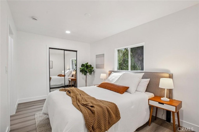 bedroom with recessed lighting, baseboards, a closet, and wood finished floors