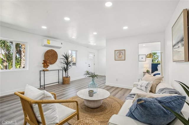 living area featuring light wood-type flooring, recessed lighting, a healthy amount of sunlight, and a wall unit AC