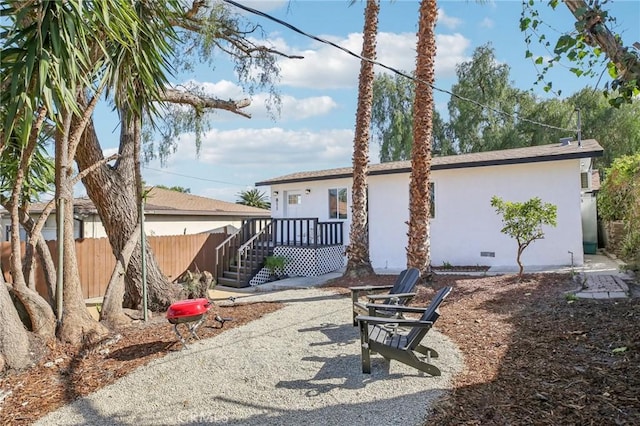 back of house with stucco siding, crawl space, and fence