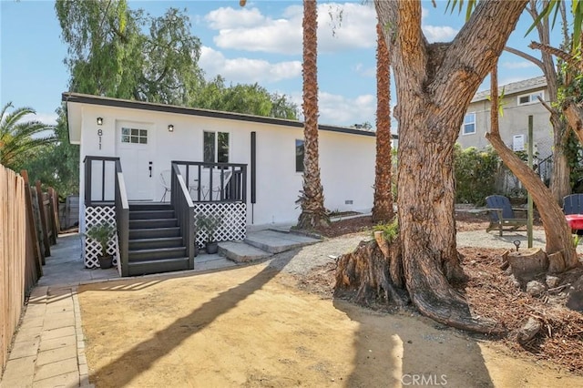 view of front of home featuring stucco siding, fence, and a wooden deck
