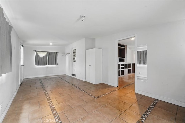 empty room featuring baseboards and light tile patterned flooring