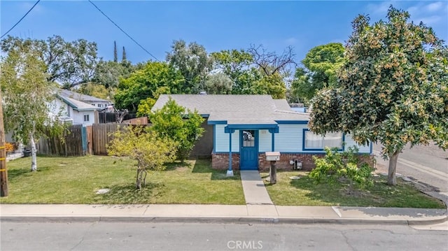 bungalow-style house featuring roof with shingles, brick siding, a front lawn, and fence