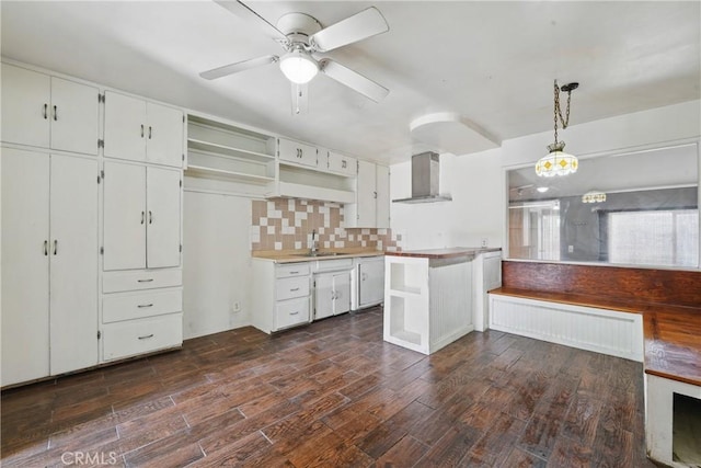 kitchen featuring open shelves, a sink, wall chimney exhaust hood, and dark wood-type flooring