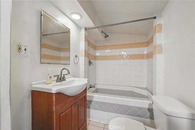 full bathroom featuring toilet, tiled shower / bath, vanity, and tile patterned flooring
