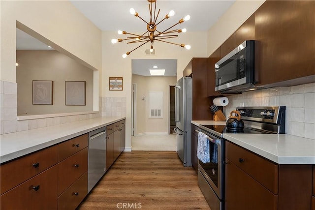44 Corniche Dr Unit G, Dana Point, CA 92629 - kitchen with appliances with stainless steel finishes, light countertops, backsplash, wood finished floors, and a chandelier