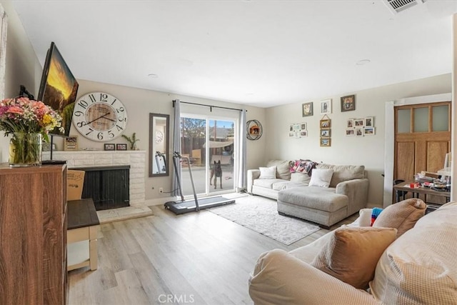 2111 Sanford St, Oxnard, CA 93033 - living room with light wood-style floors, visible vents, and a brick fireplace