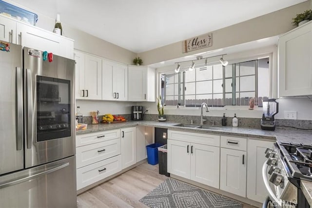 2111 Sanford St, Oxnard, CA 93033 - kitchen featuring a sink, appliances with stainless steel finishes, white cabinetry, light stone countertops, and light wood-style floors