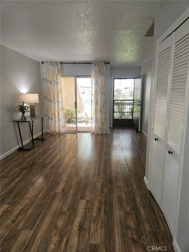 unfurnished room featuring dark wood finished floors, visible vents, baseboards, and a textured ceiling