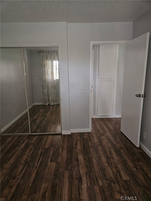 unfurnished bedroom featuring baseboards, a closet, and wood finished floors