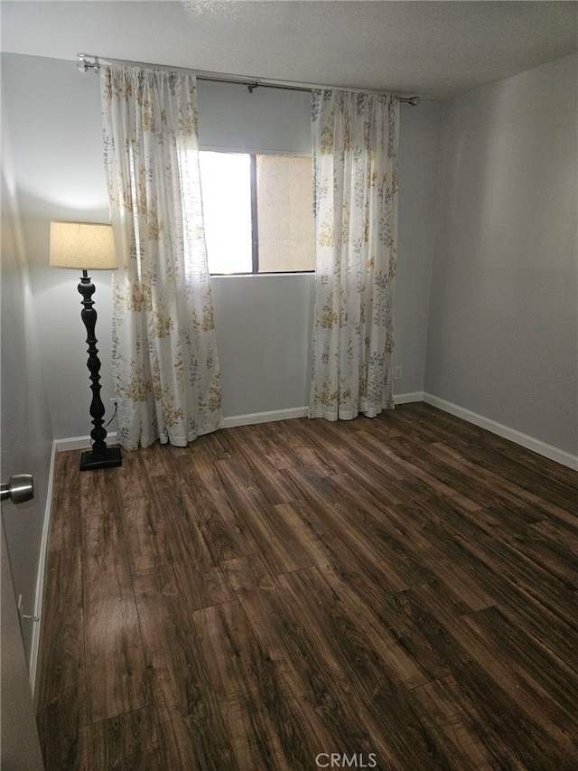 empty room featuring wood finished floors and baseboards