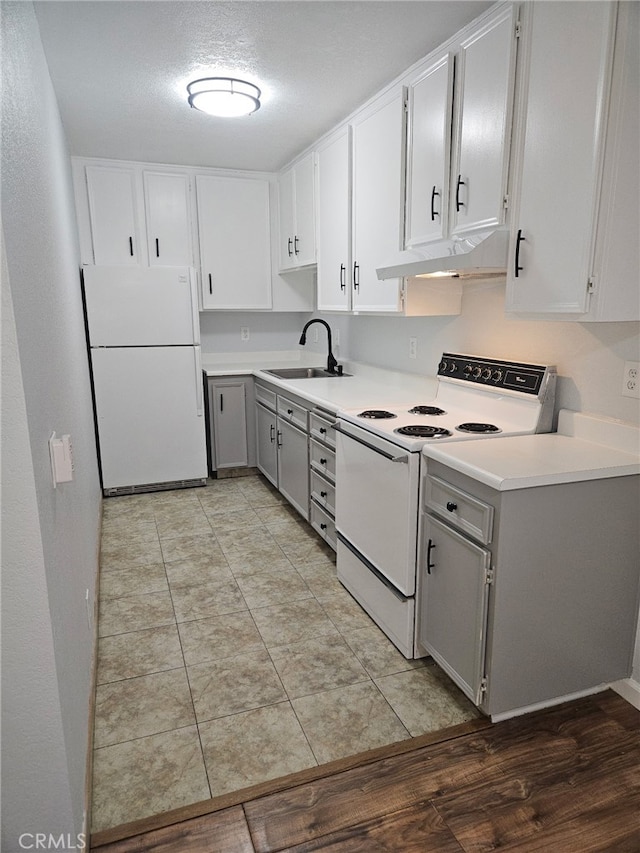 kitchen with under cabinet range hood, white appliances, a sink, light countertops, and gray cabinets