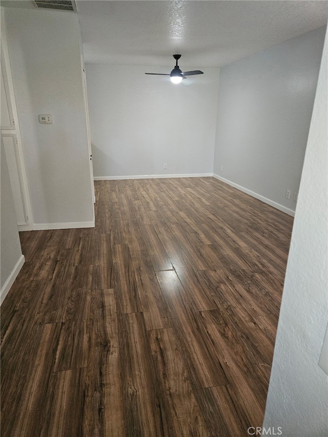 spare room with dark wood-type flooring, baseboards, visible vents, and ceiling fan