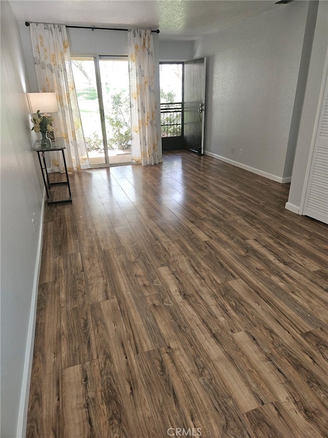 unfurnished room featuring baseboards and dark wood-type flooring