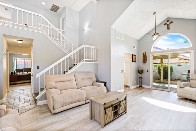 9387 Hot Springs Rd, Corona, CA 92883 - living room featuring a ceiling fan, high vaulted ceiling, light wood-type flooring, visible vents, and stairs