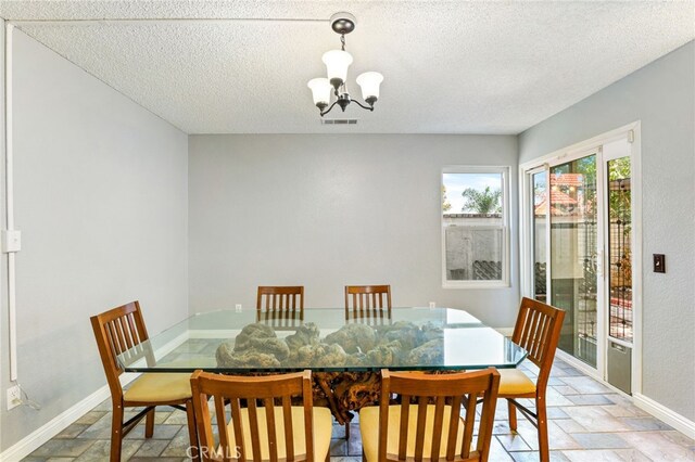 9387 Hot Springs Rd, Corona, CA 92883 - dining room featuring stone tile floors, a textured ceiling, baseboards, and an inviting chandelier