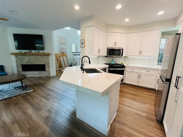 kitchen featuring a peninsula, a sink, open floor plan, white cabinetry, and appliances with stainless steel finishes