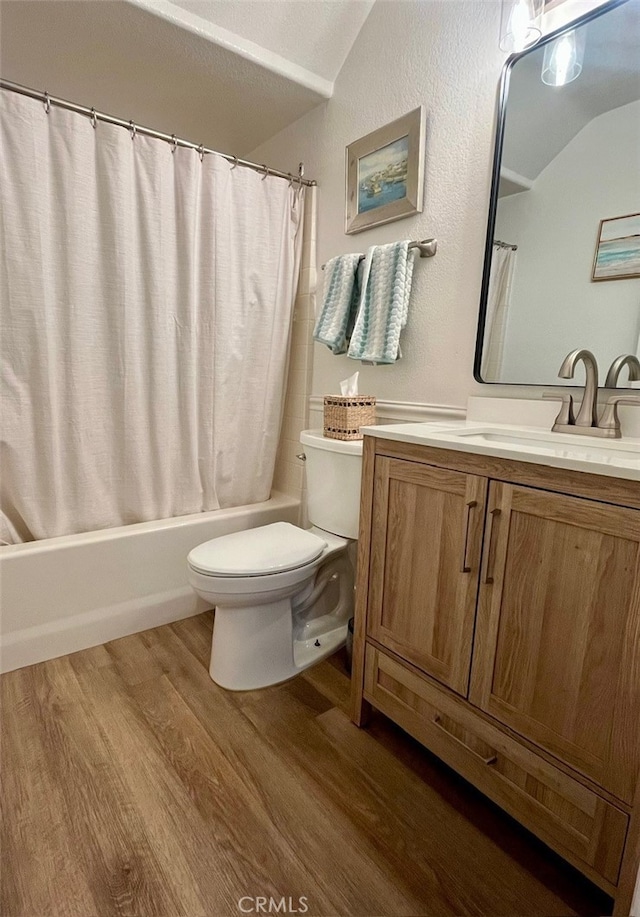 full bath with toilet, wood finished floors, lofted ceiling, shower / bathtub combination with curtain, and vanity