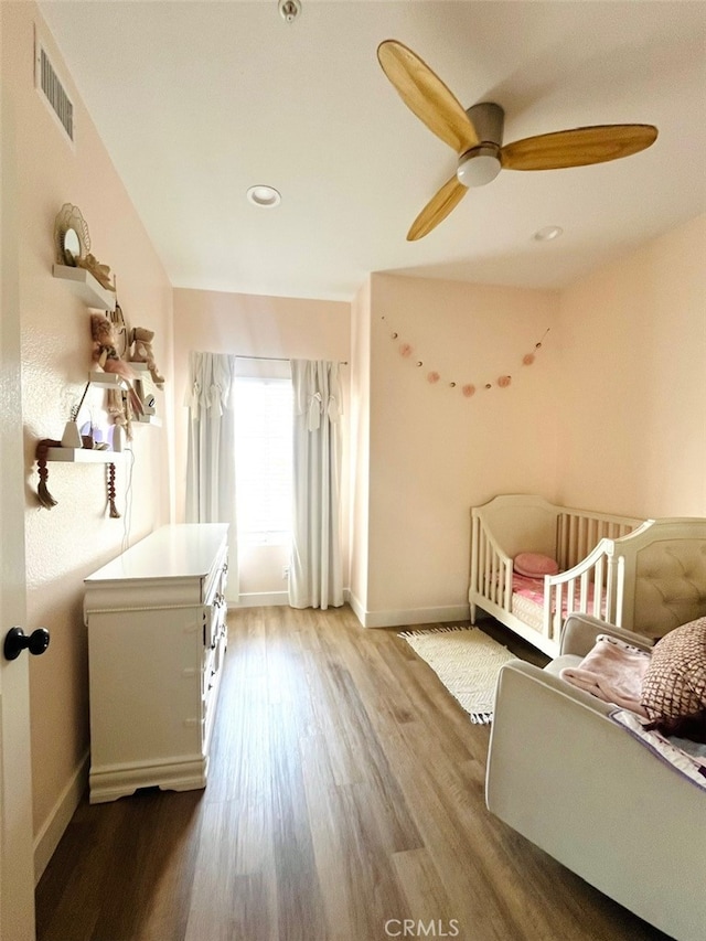 bedroom featuring ceiling fan, baseboards, visible vents, and wood finished floors