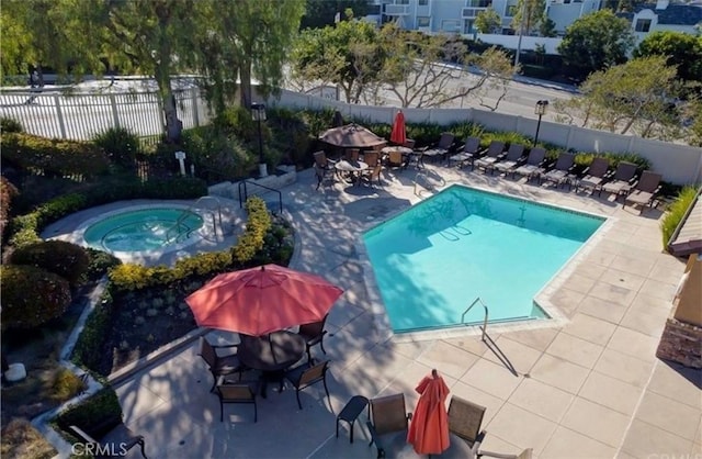 community pool featuring a patio area, a hot tub, and fence