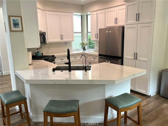 1129 W Capitol Dr Unit 29, San Pedro, CA 90732 - kitchen with black appliances, a sink, a peninsula, dark wood-style floors, and white cabinetry