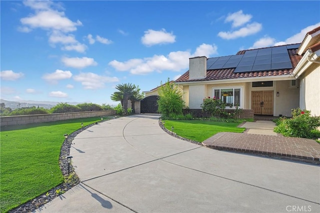 view of front facade with a tile roof, stucco siding, a front lawn, and solar panels