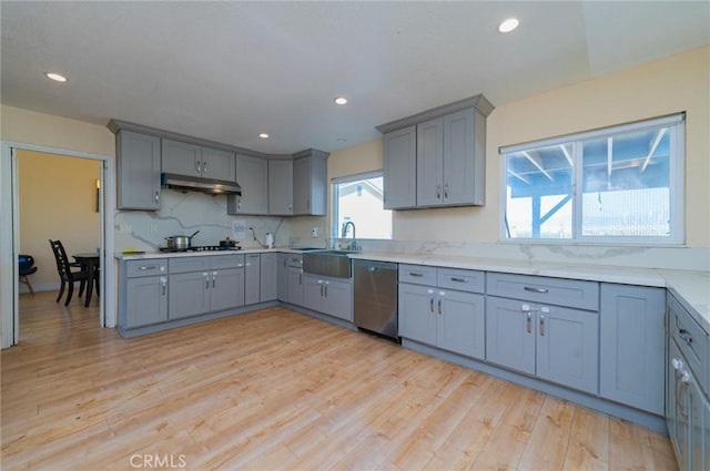 kitchen with under cabinet range hood, stainless steel dishwasher, light wood-type flooring, and gray cabinets