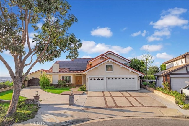 view of front of house with a garage, stucco siding, a tile roof, concrete driveway, and roof mounted solar panels