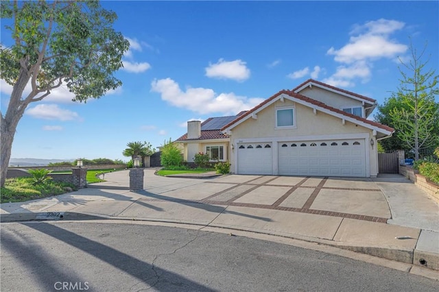 traditional home with a tile roof, stucco siding, driveway, and solar panels