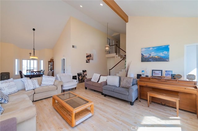 living area with light wood-type flooring, stairway, and high vaulted ceiling