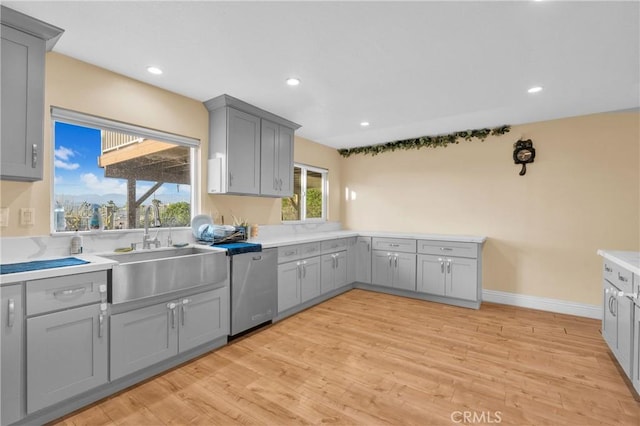 kitchen with light wood-style flooring, gray cabinetry, a sink, and dishwasher