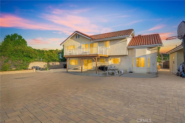 rear view of house with a patio, a tile roof, and stucco siding