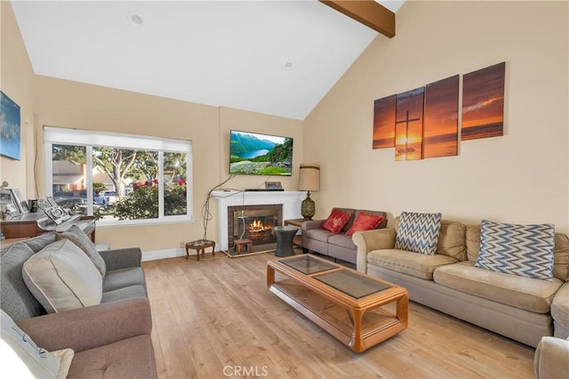 living area with light wood-style flooring, high vaulted ceiling, baseboards, beamed ceiling, and a glass covered fireplace