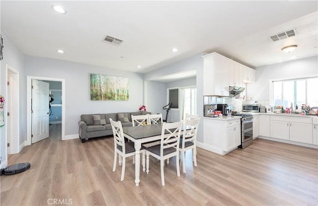 dining room with light wood-type flooring, a wealth of natural light, and visible vents