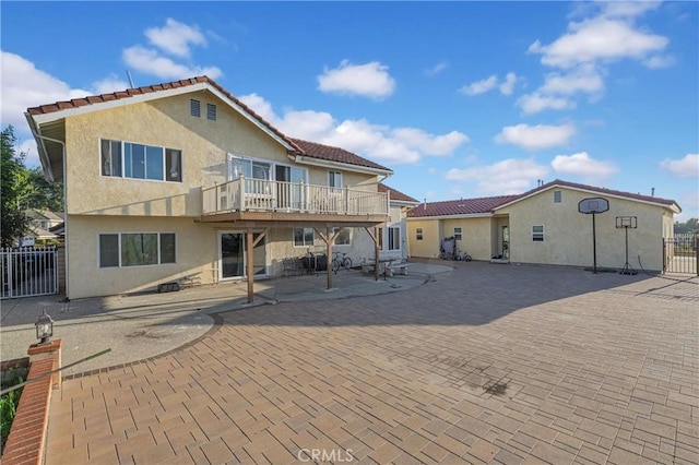 rear view of house with a patio area, stucco siding, a deck, and fence