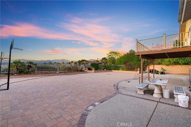 patio terrace at dusk featuring fence and a deck