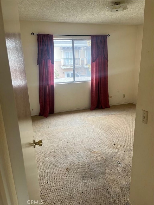 carpeted spare room with a textured ceiling
