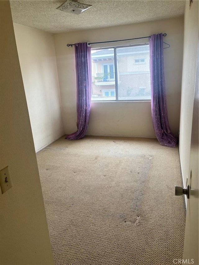 carpeted empty room featuring a textured ceiling and visible vents
