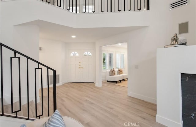 foyer entrance with wood finished floors, a high ceiling, visible vents, baseboards, and stairs