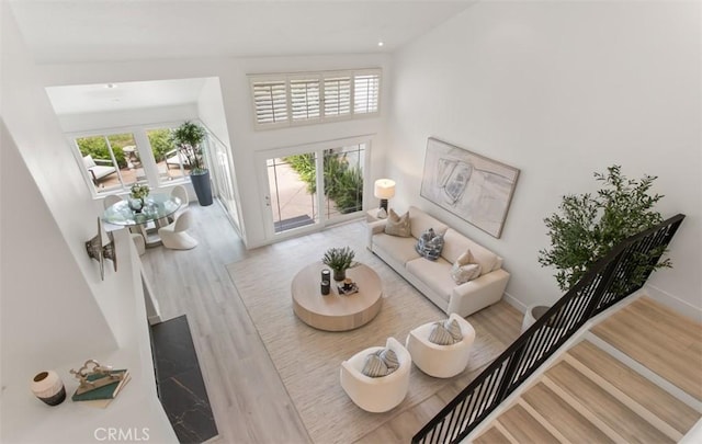 living area with wood finished floors, baseboards, and a high ceiling